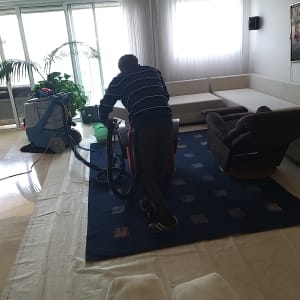 אדם מנקה שטיח עם מכונת ניקוי מקצועית