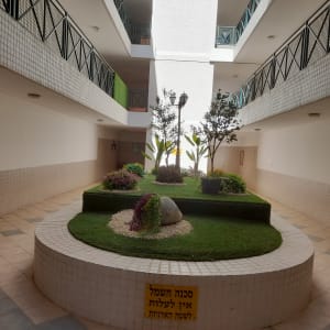 גינה פנימית עם עצים, שיחים ודשא מלאכותי