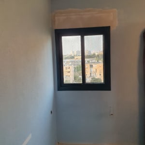 חלון אלומיניום עם רשת בחדר צבוע
