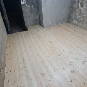 רצפת עץ חדשה בחדר עם קירות בטון חשופים