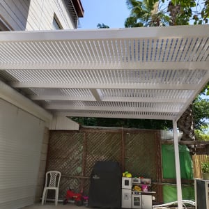 פרגולה מאלומיניום עם קורות לבנות בחצר