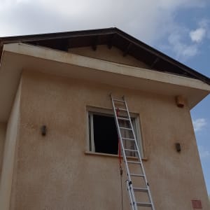 סולם מונח על קיר בית ליד חלון פתוח