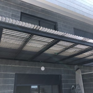 סככת מתכת מחוברת לקיר בניין אפור