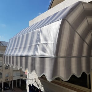 סוכך פסים אפור מותקן על קיר חיצוני