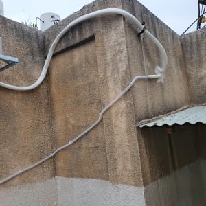 יחידת מזגן חיצונית עם צינורות על קיר