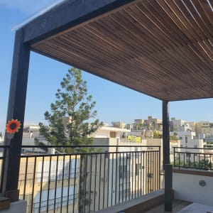 פרגולה מעץ עם קורות עץ על מרפסת