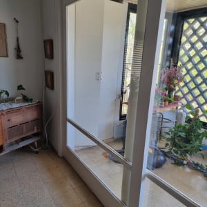 דלת זכוכית עם מסגרת לבנה מובילה למרפסת