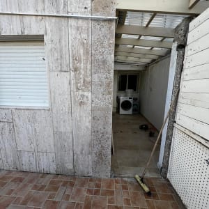 קיר עם סדק, מטאטא על הרצפה, מכונת כביסה ברקע