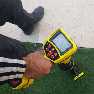 אדם מחזיק מכשיר לגילוי נזילות עם מסך ותצוגה דיגיטלית