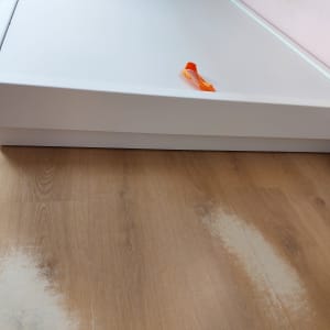 מיטה לבנה עם ידית כתומה על רצפת עץ