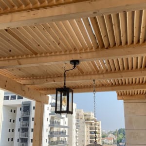 פרגולה מעץ עם מנורת תלייה על מרפסת