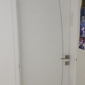 דלת לבנה עם ידית מתכת ועיצוב קו מעוקל