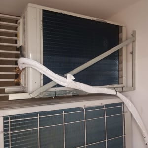 יחידת מיזוג אוויר חיצונית מותקנת על קיר עם צינור לבן