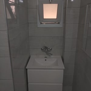 כיור לבן עם ברז מתכת, חלון קטן מעל