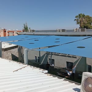 התקנת סוכך כחול על גג עם אנשים ברקע