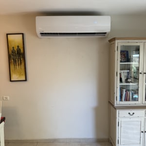 מזגן עילי לבן מותקן על קיר בחדר מגורים
