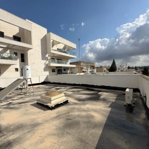 גג שטוח עם חומרי איטום ומבנים סמוכים