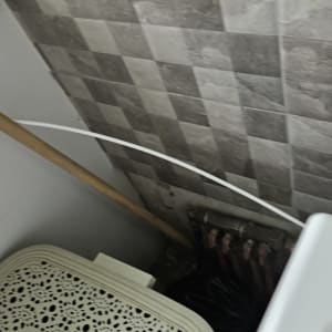 צינור לבן ליד קיר אריחים אפור