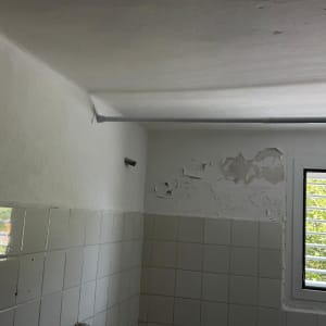 קיר עם טיח מתקלף ליד חלון עם תריסים