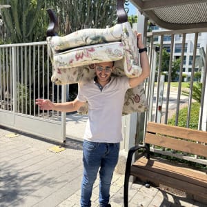 תמונה של אדם נושא כורסה על ראשו ברחוב