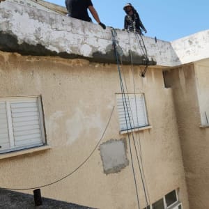 שני אנשים עובדים על גג עם חבלים וציוד בטיחות