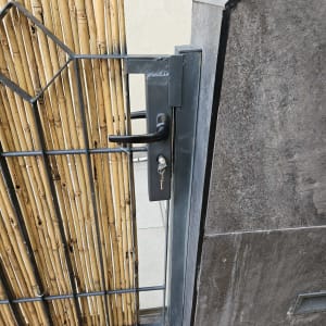 שער מתכת עם מנעול ומפתח, ליד קיר במבוק