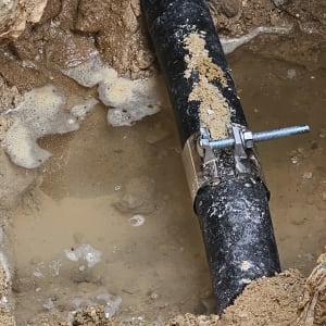 תיקון צינור מים עם תפסן מתכת באדמה רטובה