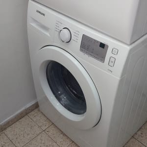 מכונת כביסה לבנה עם כפתורים ותצוגה דיגיטלית