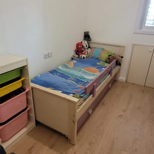 מיטת ילדים עם מצעים צבעוניים וצעצועים