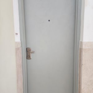 דלת אפורה עם ידית כסופה בקיר לבן