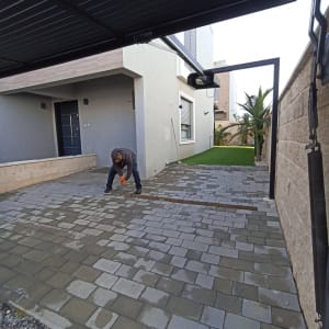 אדם עובד על ריצוף חצר עם אבנים משתלבות