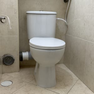 אסלה מותקנת בחדר אמבטיה עם חיבורי צנרת