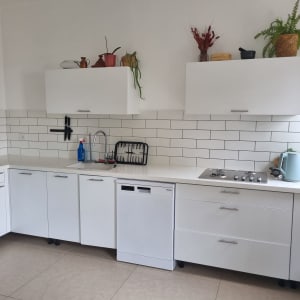 מטבח מודרני עם ארונות לבנים ומשטח עבודה