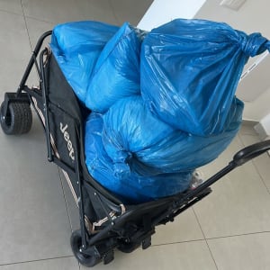 עגלת משא עמוסה בשקיות אשפה כחולות לאחר פינוי וניקוי