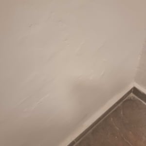 קיר עם טיח לא אחיד ליד רצפה