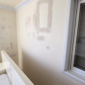 קיר עם תיקוני צבע וטיח ליד חלון