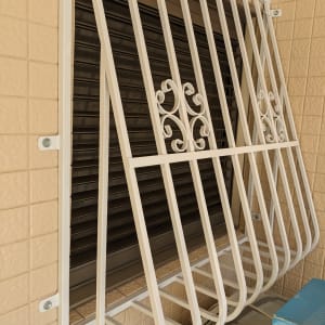 סורגי מתכת לבנים על חלון עם תריסים סגורים