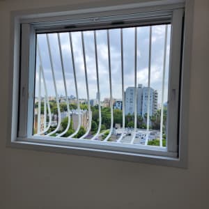 חלון עם סורגים לבנים ונוף עירוני ברקע