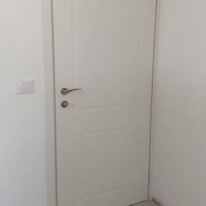 דלת לבנה עם ידית כסופה על קיר לבן