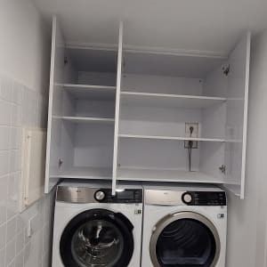 ארונות פתוחים מעל מכונת כביסה ומייבש