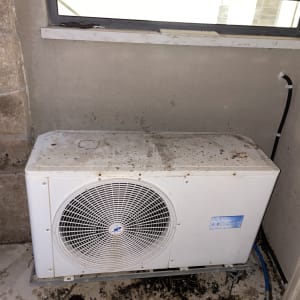 יחידת מיזוג אוויר מלוכלכת ליד חלון קטן