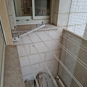 מתקן כביסה מותקן על קיר מרפסת עם חבלים