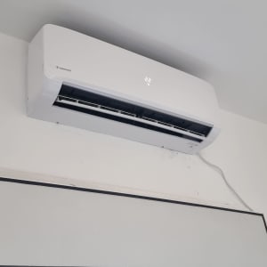 מזגן קיר לבן מותקן על קיר עם תצוגת טמפרטורה