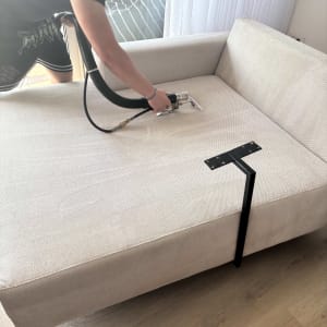 אדם מנקה ספה עם מכשיר ניקוי