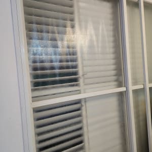 חלון זכוכית עם תריסים מאחוריו