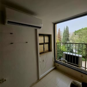 מזגן מותקן על קיר ליד חלון פתוח