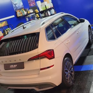 רכב לבן בחדר דיטיילינג עם מוצרי ניקוי על מדף