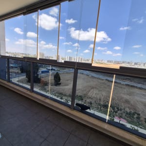 מרפסת עם חלונות זכוכית ונוף לעיר