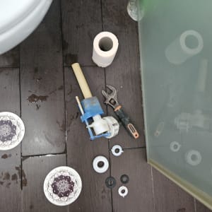 כלי עבודה וחלקי אינסטלציה על רצפה רטובה