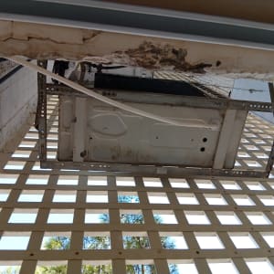 יחידה חיצונית של מזגן מותקנת על תושבת מתכת עם צינור ניקוז מחובר